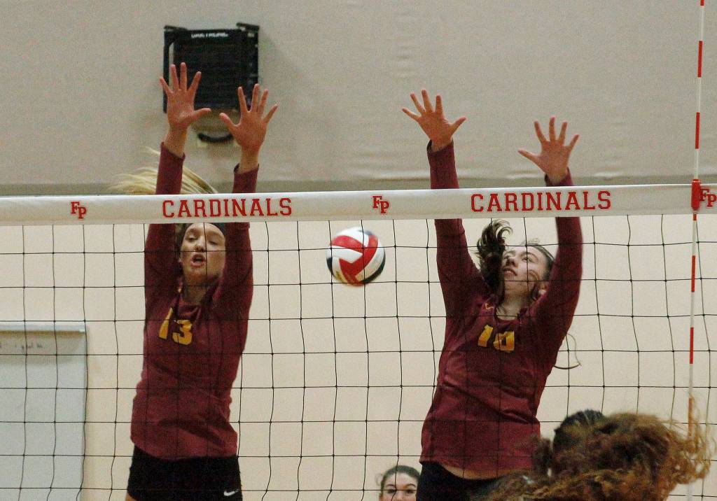 Morgan Halady (13) and Abby Steele (10) of Kingston team up for a block attempt against Fife. (Mark Krulish/Kitsap News Group)
