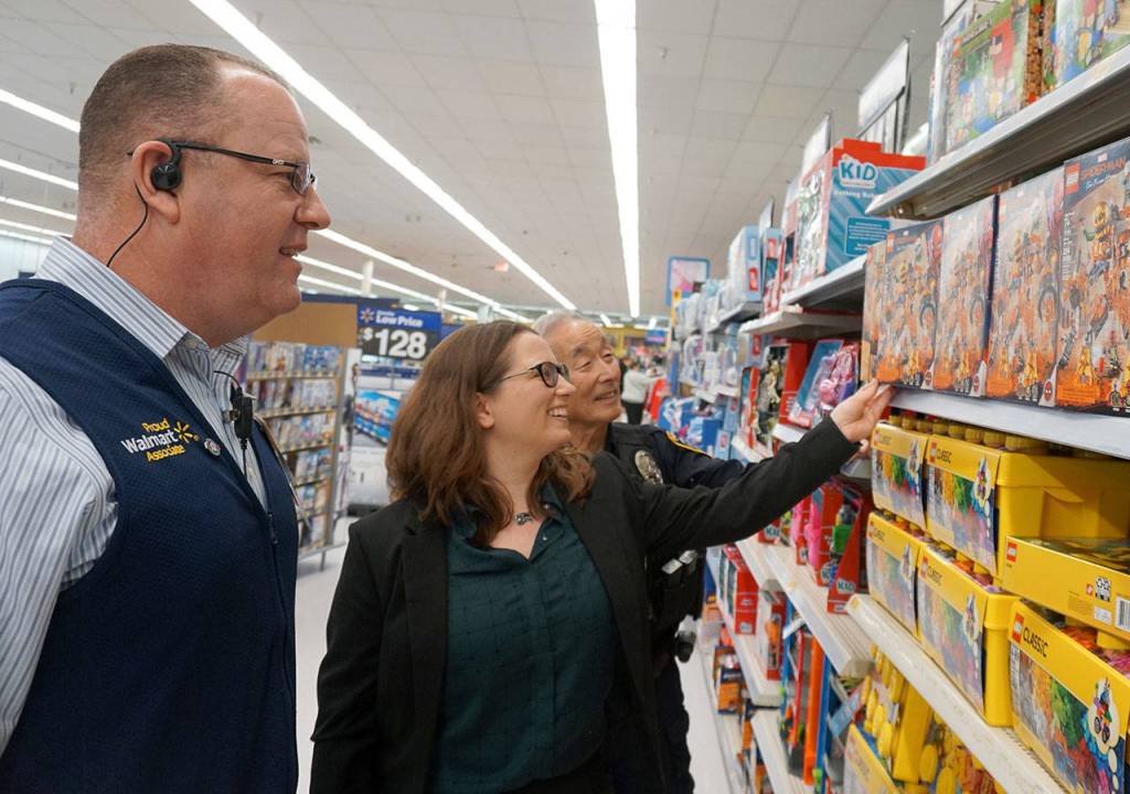 Walmart manager Doug Goodin and Port Orchard Police Department officers Amy Coull and Cliff Higashi check out game selections for adolescents as part of the Giving Tree program the department is coordinating with South Kitsap Helpline. Dozens of families in South Kitsap will be the happy recipients of the gifts collected by residents this month. (Bob Smith | Kitsap Daily News)