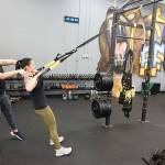 Annapolis Fitness Performance co-owners Sydnie Kittelson (left) coaches Kristi McGee on a TRX row. (Mike De Felice photo)
