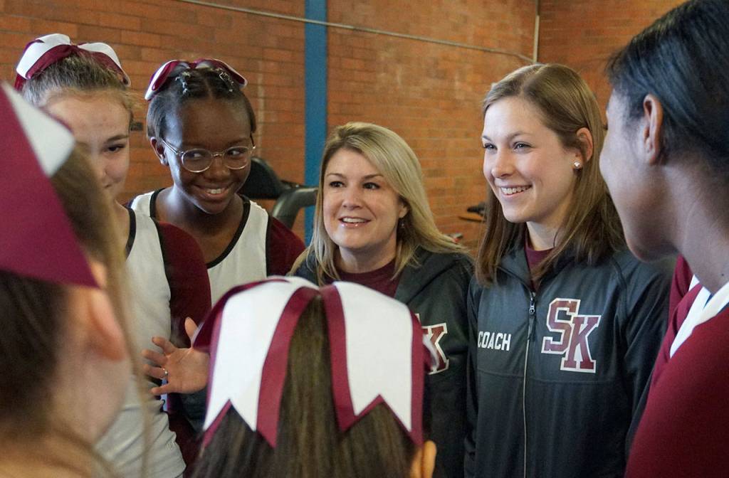 South Kitsap cheer coach Heather Hays (center) and assistant coach Merissa Ekman (inside right) huddle with the team prior to heading out to perform in a boys basketball playoff game against Rogers Feb. 8. (Bob Smith | Kitsap Daily News)