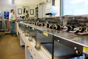 Harry Turnbull, extra help lead with the Kitsap County Elections Division, sends a batch of ballot envelopes through a processing reader prior to counting the ballots inside. (Bob Smith | Kitsap News Group 2018)