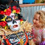 Alice Taylor, 4, of Port Orchard found her favorite scarecrow  a creation highlighted by a colorfully painted face mask, submitted in 2019 by Home Made Cafe in the scarecrow contests Business category. (Bob Smith | Kitsap Daily News 2019)