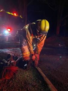 After working to extinguish a brush fire in a Little Boston ravine for over two hours, NKF&R firefighter Justin Slye rolls up one of the multiple sections of hose that was used. NKF&R courtesy photos