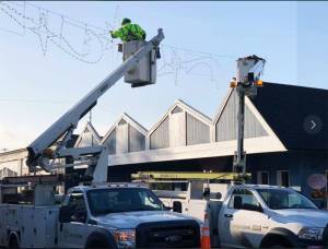 Workers hang Christmas lights above the streets in Poulsbo. Ken Park/Kitsap Daily News