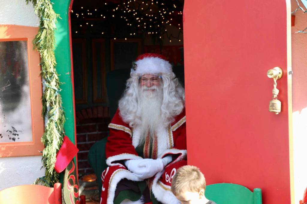 Santa sits serenely just inside his cottage, smiling as a small boy plucks up the courage to tell Santa what he wants for Christmas. KPark/NKH