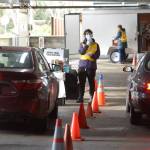 Suquamish Tribe Community Health nurse Mickenzy Cordova directs the next Tribal Elder into the shot station at the Tribe’s drive-thru vaccination clinic at Port Madison Indian Reservation on Tuesday. (Jon Anderson)