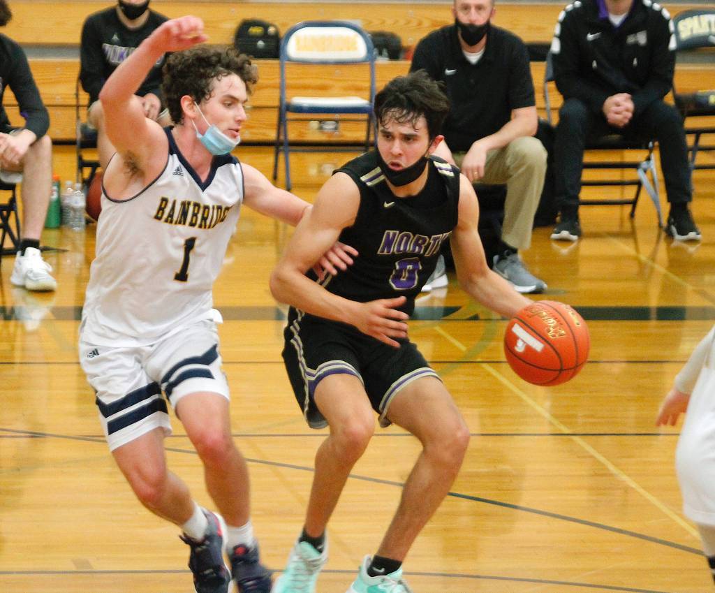 Johny Olmsted (0) is guarded closely by Bainbridge senior Jacob Kirsch (1). (Mark Krulish/Kitsap News Group)