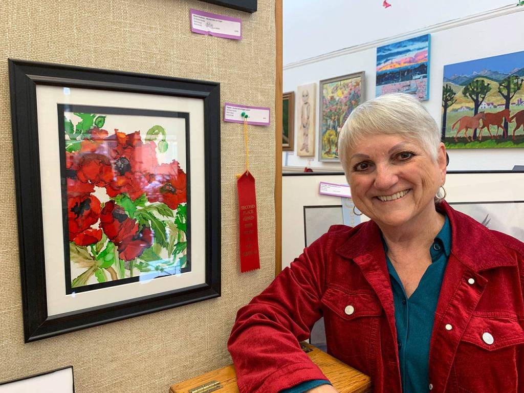 South Kitsap Art Association member Sherry Beck stands in front of artwork she created, now on display at the Sidney Art Gallery in Port Orchard. (Bob Smith | Kitsap Daily News)
