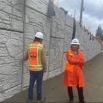 Dian Lenius, Poulsbos director of Engineering, inspects the walls that separate the road from the shared-use path on the roundabout project.