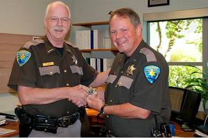 Now retired Kitsap County Sheriff Gary Simpson presents John Gese with a new sheriffs badge following the announcement of Geses appointment as interim sheriff. Gese was appointed Kitsap County sheriff Monday by the Board of Commissioners. (File photo)