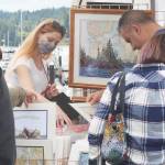 Visitors look at artwork at one of the booths. Steve Powell/North Kitsap Herald