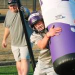 Sophomore Kaden Pickard takes on the tackling dummy as head coach Jeff Weible looks on during practice. (Mark Krulish/Kitsap News Group)
