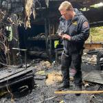 Deputy Fire Marshal Greg Gentile examines the scene and photographs key elements after a fire gutted a travel trailer Tuesday.