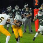 Bainbridge quarterback Jack Grant, left, hands off to Garrett Goade as Port Angeles defender Jeremiah Hall closes in on Friday night in Port Angeles. (Keith Thorpe/Olympic Peninsula News Group)
