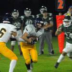 Bainbridge quarterback Jack Grant, left, hands off to Garrett Goade as Port Angeles defender Jeremiah Hall closes in on Friday night in Port Angeles. (Keith Thorpe/Olympic Peninsula News Group)