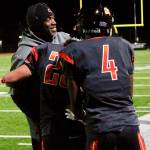 Head coach Mark Keel and Josiah Johnson (4) congratulate Kouper Hall after he reached the 1,000-yard milestone. (Mark Krulish/Kitsap News Group)