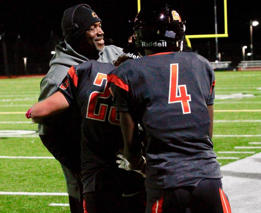 Head coach Mark Keel and Josiah Johnson (4) congratulate Kouper Hall after he reached the 1,000-yard milestone. (Mark Krulish/Kitsap News Group)