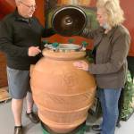 Stuart Chisholm and Mary Ellen Houston peer inside a large clay pot, where the juice of the grapes will ferment. (Bob Smith | Kitsap Daily News)