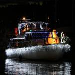 The Christmas lights reflect nicely in the water on this boat.