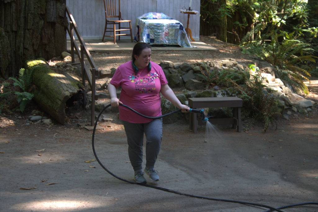 Cast member Carol Stanley sprays down the stage area to prevent dust from flying up at the actors and the audience.
