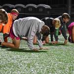 The midnight practice began with routine stretches on the football field.
