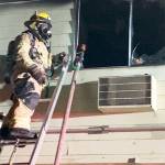 A firefighter climbs a ladder to battle the blaze.