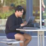 A student sits at one of the outside tables to attend to schoolwork.