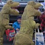 Two kids make their way through a trunk or treat as a pair of dinosaurs.