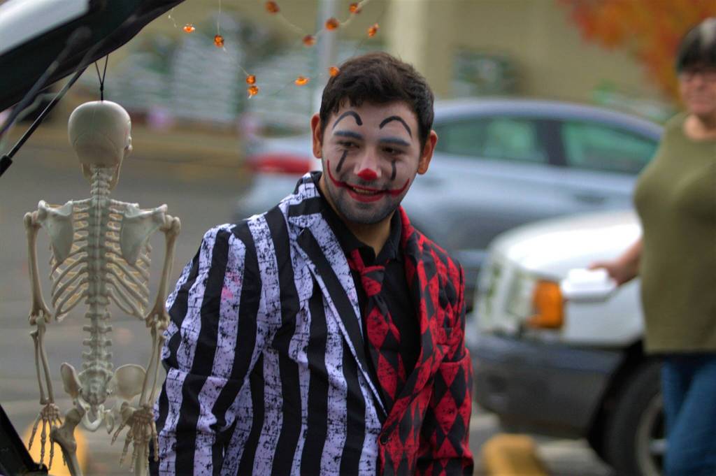 A trunk or treat vendor greets visitors to his car with some scary visuals and some candy as well.