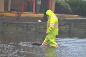 A city worker picks up debris swept up by floodwaters. Elisha Meyer/Kitsap News Group Photos