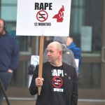Local politician Rick Kuss holds a sign with the same message as his recently marketed shirt in protest of the plea agreement in a rape case.