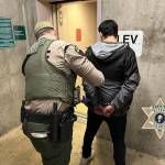 The robbery suspect is led away by an officer with the Kitsap County Sheriff's Office.