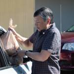 Sunnyslope Elementary counselor Roger Mangahas loads a meal for a veteran's family into the passenger side of the car. Elisha Meyer/Kitsap News Group Photos
