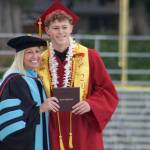 A graduate receives his diploma from superintendent Laurynn Evans.