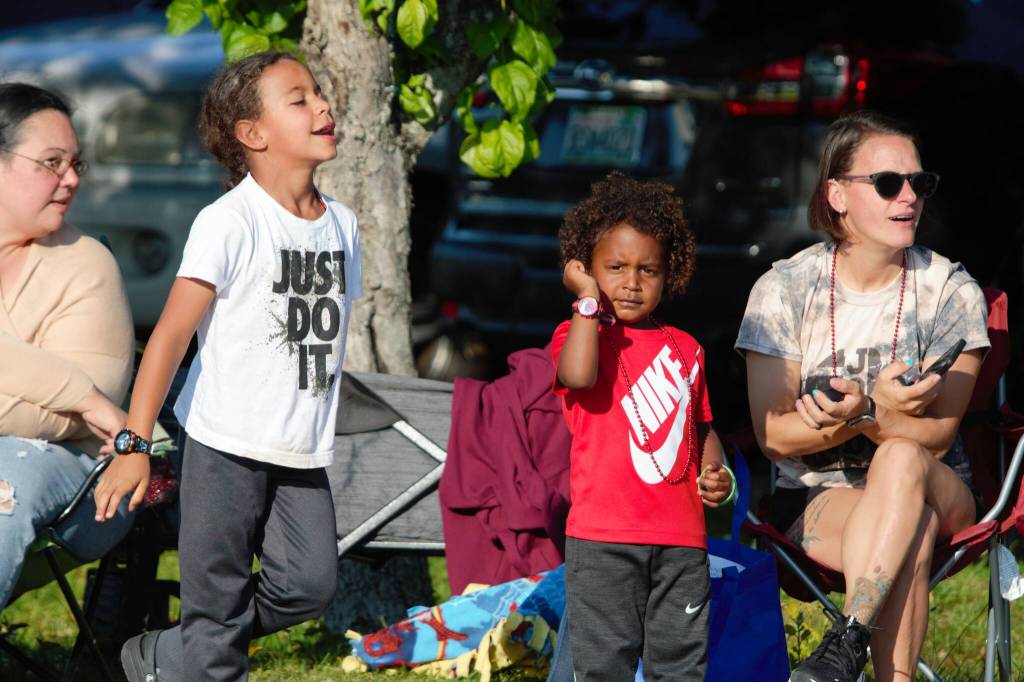 Kids call to the drivers of a classic car club to honk their horns and rev their engines.