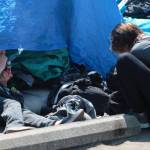 A resident of the encampment smokes a controlled substance out of a pipe.