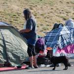 A woman walks her dog along the line of tents making up the encampment.