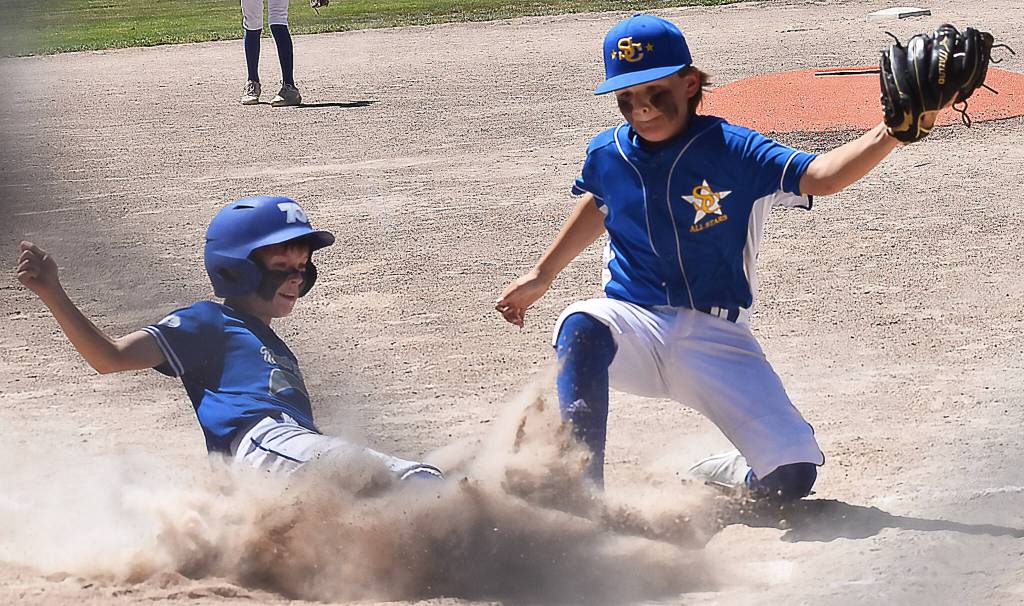 Kaiden Gilbert slides underneath the tag to score for NK. The local team won its first game 15-5, lost 11-1 in its second then won 1-0 July 17. They need to win four straight or be eliminated.