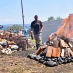 A fire piled high with wood cooks clams for the gathering.