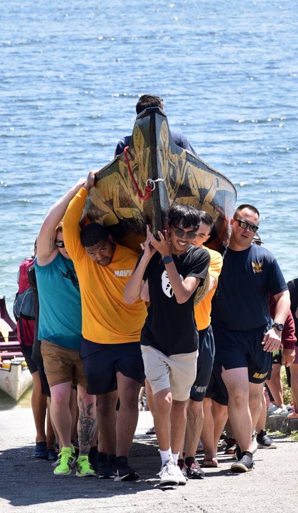 Canoes are carried up the ramp by tribal members and volunteers from the Navy.
