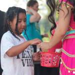 8-year-old Jordyn picks something from a basket held by one of the costumed Disney princesses.