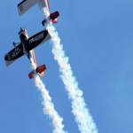 A pair of trick planes ascend into the sky.