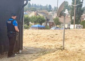 Elisha Meyer/Kitsap News Group Photos
An officer with the Bremerton Police Department keeps a watchful eye on the happenings inside a large homeless encampment.
