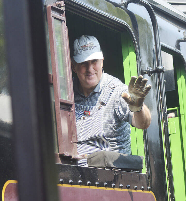 The conductor waves to passengers as they leave the train.