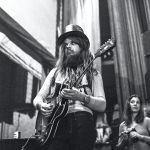 Leon Russell playing guitar as Linda Wolf looks on.