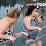 Two women prepare for the cold, standing just one step away from dropping into Olalla Bay.