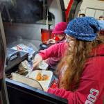 Supper consisting of chicken and vegetables is prepared for the homeless near a grocery store.