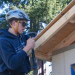 Student James Phillips secures a piece of plywood to the roof of the Hyla students tiny home project.