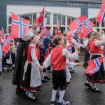 Kids dressed in traditional costumes walk along the parade route.