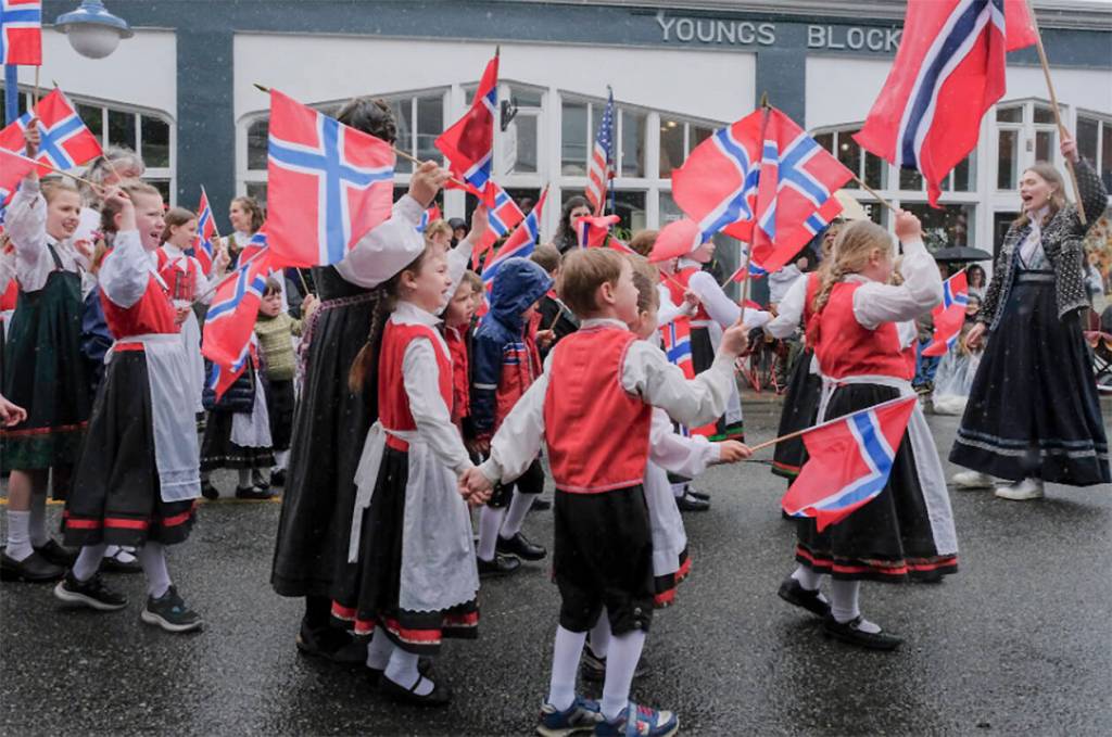 Kids dressed in traditional costumes walk along the parade route.